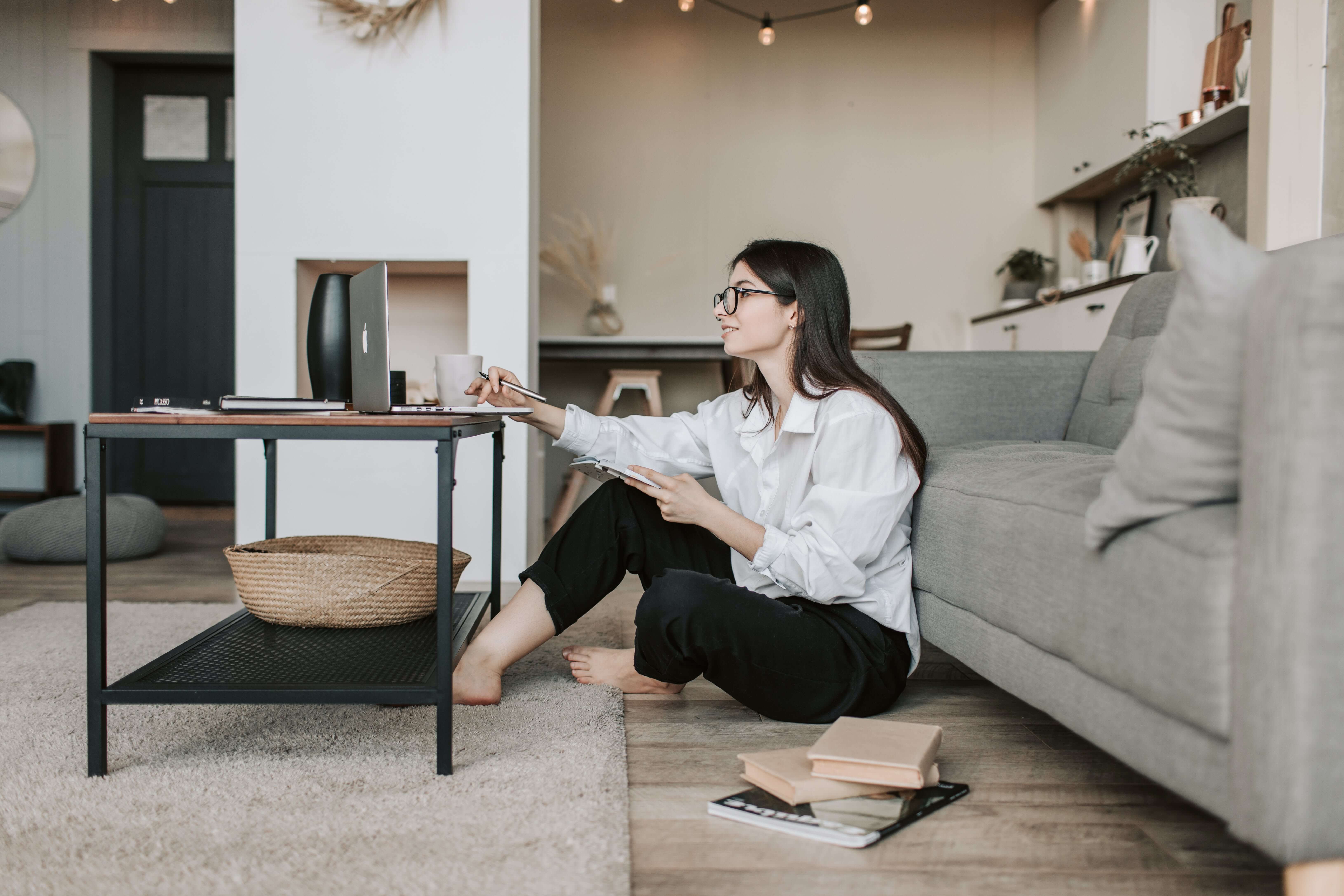 woman sitting on living room floor using laptop
